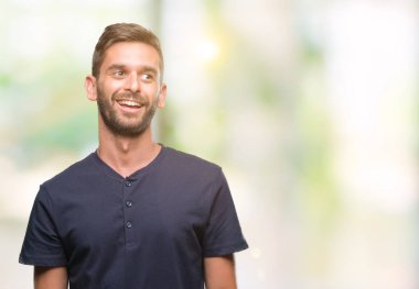 Yakışıklı delikanlı uzak tarafına yüzünde, doğal ifade gülümseme ile seyir izole arka plan üzerinde. Kendine güvenen gülüyor.