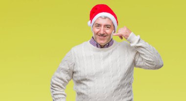 Üst düzey yakışıklı Noel şapka yapmayı gülümseyen izole arka plan üzerinde telefon hareketi ile el ve parmak telefonda konuşuyor gibi. Kavramları iletişim.