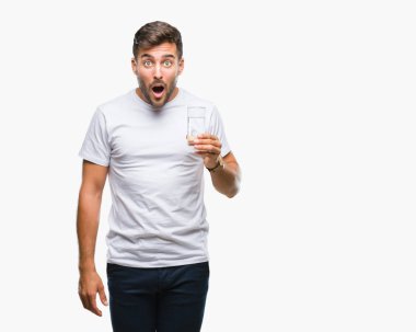 Yakışıklı delikanlı izole arka şok sürpriz yüzü, korkuyor ve korku ifadesi ile heyecanlı olan korkmuş üzerinde bardak su içme