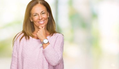 Emin çapraz kollar ve çeneme kaldırdı el ile gülümseme ile kameraya bakarak izole arka plan üzerinde kış kazak giyen güzel orta yaş yetişkin kadın. Pozitif düşünce.