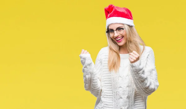 笑顔と成功のために叫んで 上クリスマスの帽子を着ている若い美しいブロンドの女性は非常に幸せと興奮の腕を上げ 勝者のジェスチャを行う背景を分離しました お祝いのコンセプト — ストック写真