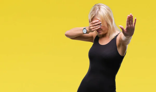 Young beautiful blonde attractive woman wearing elegant dress over isolated background covering eyes with hands and doing stop gesture with sad and fear expression. Embarrassed and negative concept.
