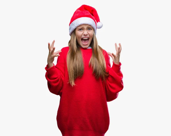 年轻美丽的女孩戴着圣诞节帽子在孤立的背景疯狂和疯狂的呼喊和咆哮与积极的表达和武器提出 挫折概念 — 图库照片