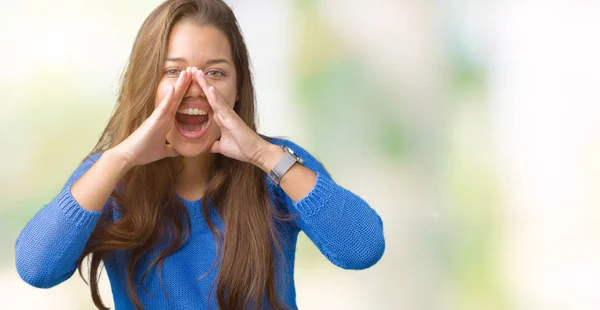 年轻美丽的黑发女人穿着蓝色毛衣在孤立的背景大喊愤怒大声与手在嘴 — 图库照片