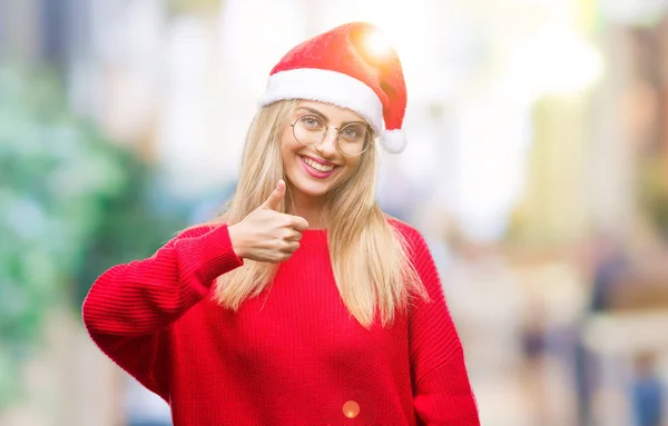 年轻美丽的金发女子戴着圣诞节帽子在孤立的背景做愉快的拇指手势与手 批准表达式看着相机显示成功 — 图库照片
