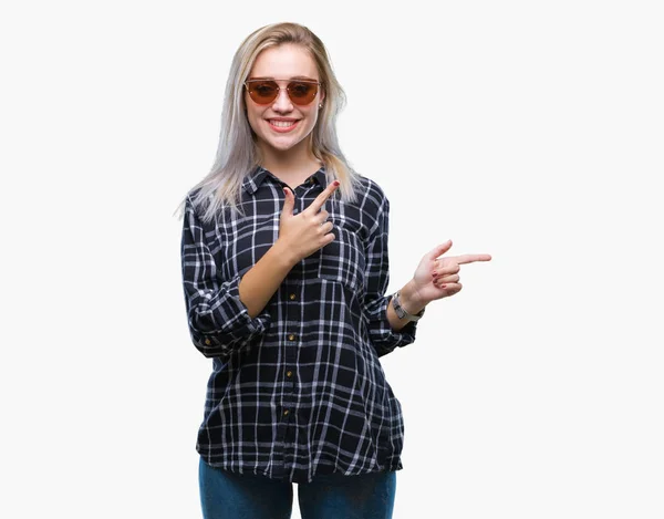笑顔で側に つの手と指で指しているカメラを見て孤立の背景の上にサングラスをかけている若いブロンドの女性 — ストック写真