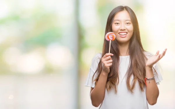 Молодая Азиатская Женщина Ест Конфеты Леденец Изолированном Фоне Счастливый Взволнованный — стоковое фото