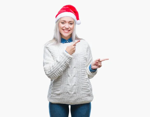 分離背景笑顔で側に つの手と指で指しているカメラ目線の上クリスマス帽子身に着けている若いブロンドの女性 — ストック写真