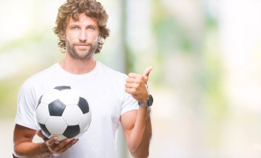 İspanyol yakışıklı modeli futbol futbol topu tutan arka plan mutlu ok işareti, başparmak ile parmak, mükemmel işareti yapıyor kocaman bir gülümseme ile izole