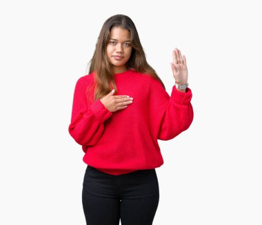 Arka plan üzerinde kırmızı kış kazak giyen genç güzel esmer kadın izole göğüs ve bir sadakat sözü yemin yapma avuç, el ile küfür