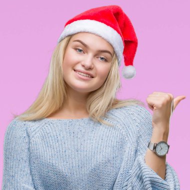 Seyir ve başparmak yanında yukarıyı mutlu yüz ile gülümseyen izole arka plan üzerinde Noel şapka giyen genç beyaz kadın.