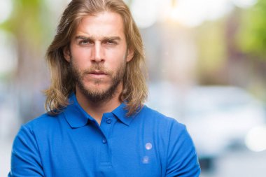 Yakışıklı delikanlı izole arka plan şüpheci ve sinir, onaylamayan ifade yüz çapraz kolları olan uzun saçlı. Negatif kişi.