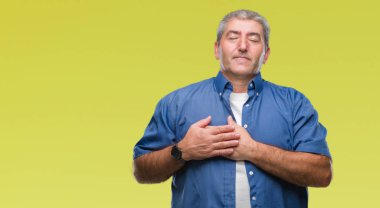 Göğüs kapalı gözler ve yüzünde minnettar jest ile üst düzey yakışıklı ile gülümseyen izole arka plan üzerinde eller. Sağlık kavramı.