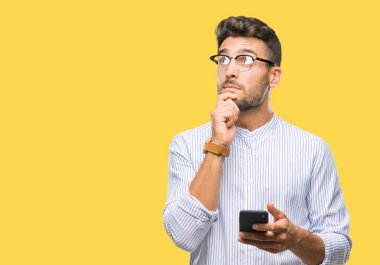 Genç yakışıklı adam akıllı telefon kullanan izole arka plan ciddi bir yüz düşünme hakkında soru, çok karışık fikir üzerinden manifatura
