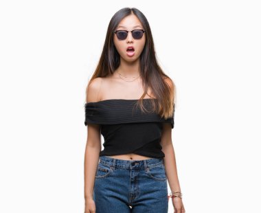 Genç Asyalı kadın korkuyor ve şok sürpriz ifade, korku ve heyecan yüz ile izole arka plan üzerinde güneş gözlüğü takıyor.