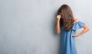 Grunge gri duvar yorgun sürtünme burun ve göz yorgunluğu ve baş ağrısı duygu genç İspanyol çocuk. Stres ve hayal kırıklığı kavramı.