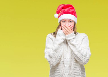 Üzerinde Noel şapka giyen genç güzel beyaz kadın arka plan ağız hata için elleriyle kapsayan şok izole. Gizli kavramı.