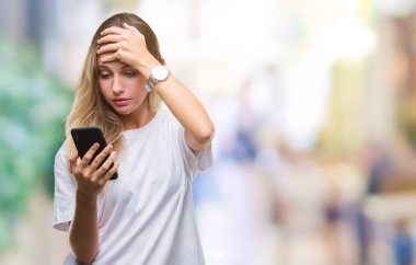 Baş, el ile vurguladı izole arka plan üzerinde akıllı telefon kullanan genç güzel sarışın kadın şok utanç ve sürpriz suratla, öfkeli ve sinirli. Korku ve hata için üzgün.