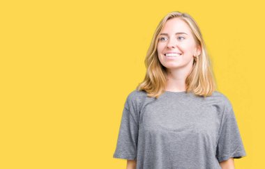 Uzak tarafına yüzünde, doğal ifade gülümseme ile seyir izole arka plan üzerinde büyük boy rahat t-shirt giyen güzel ve genç birbayan. Kendine güvenen gülüyor.