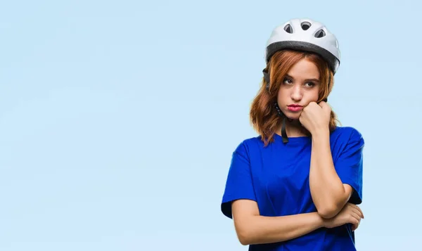 年轻的美丽的女人戴着骑自行车的头盔在孤立的背景认为疲惫和厌倦与交叉的手臂抑郁症的问题 — 图库照片