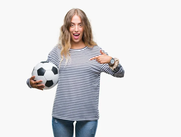 自分自身に驚き顔ポインティング指で孤立した背景にサッカー サッカー ボールを保持している美しい若いブロンドの女性 — ストック写真