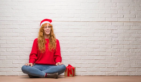 Young Redhead Woman Sitting Brick Wall Wearing Christmas Hat Winking — Stock Photo, Image