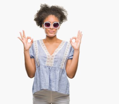 Genç afro Amerikalı kadın gözlük izole arka plan üzerinde dinlenmek ve gülümseyen gözlerle kapalı parmak jestle meditasyon yapıyor. Yoga kavramı.