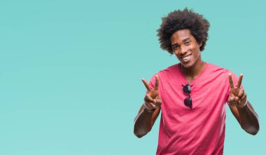 Zafer işareti yapıyor parmak gösterilen kamera seyir gülümseyen izole arka plan üzerinde Afro Amerikalı adam. İki numaralı.