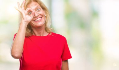 Orta yaş sarışın kadın gülümsüyor, parmakları ile mutlu yüz üzerinden seyir göz el ile ok jest yapıyor izole arka plan üzerinde.