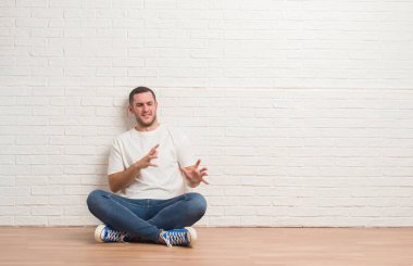 Beyaz tuğla duvarın üzerinden katta oturan genç beyaz adam tiksinti ifadesi, memnun ve korkulu tiksinti yüz yapıyorsun çünkü nefret tepki. Elleriyle kaldırdı. Sinir bozucu kavramı.