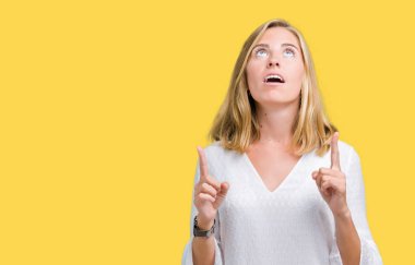 İzole arka plan güzel genç zarif kadın hayrete ve yukarıya bakıyor ve parmakları ile işaret ve silah kaldırdı şaşırttı.