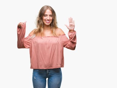 Gösterilen ve parmakları ile işaret izole arka plan üzerinde sarışın güzel genç kadın kendinden emin ve mutlu gülümseyerek süre 6 numara.