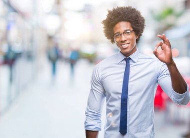 Afro Amerikan iş adamı izole arka plan el ve parmaklar ok işaretiyle yapıyor olumlu gülümseyen üzerinde gözlük takıyorum. Başarılı ifade.