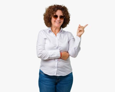 Kameraya bakarak yan el ve parmak ile işaret yüzünde kocaman bir gülümseme ile izole arka plan üzerinde güneş gözlüğü takıyor güzel orta ager üst düzey iş kadını.