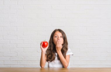 Hata, korku, sessizlik içinde gizli kavramı korkmuş ifade için utanç ile taze domates kapak ağız el ile yemek masada oturan genç İspanyol çocuğun şok