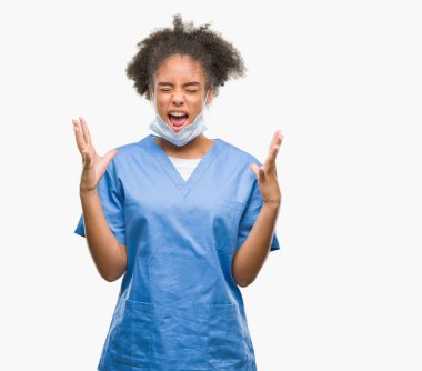 Young afro american doctor woman over isolated background celebrating mad and crazy for success with arms raised and closed eyes screaming excited. Winner concept clipart