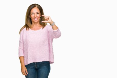 İzole arka plan gülümseyen ve boyutu işaret parmaklı ararken ve kamera işi el ile kendinden emin eller üzerinde kış kazak giyen güzel orta yaş yetişkin kadın. Ölçü kavramı.