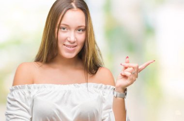 Yüzünde kocaman bir gülümseme ile izole arka plan üzerinde genç Kafkas güzel kadın kameraya bakarak yan el ve parmak ile işaret.