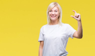 İzole arka plan gülümseyen ve süre seyir ve kamera boyutu işaret parmaklarıyla yapıyor el ile kendinden emin eller üzerinde beyaz t-shirt giyen genç güzel sarışın bir kadın. Ölçü kavramı.