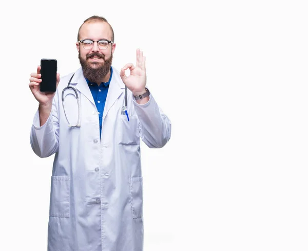 年轻的医生男子显示智能手机屏幕在孤立的背景做确定的标志与手指 优秀的符号 — 图库照片