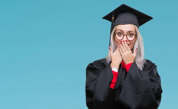 若いブロンドの女性は分離背景のミスのための手で口を覆っているショックを受けた大学院の制服を着ています 秘密の概念 — ストック写真
