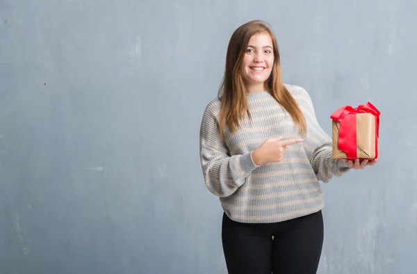 Joven Mujer Adulta Sobre Pared Grunge Gris Sosteniendo Regalo Muy —  Fotos de Stock