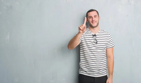 Joven Caucásico Hombre Sobre Gris Grunge Pared Mostrando Apuntando Hacia —  Fotos de Stock