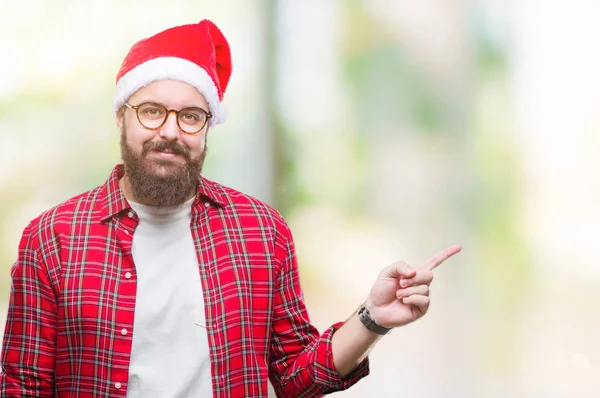 カメラを見ている側の手と指で指すの顔に大きな笑みを浮かべて隔離された背景にクリスマスの帽子をかぶって若い白人男 — ストック写真