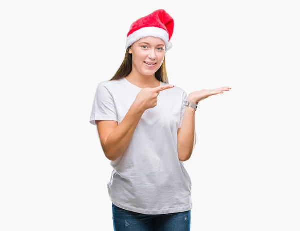 驚くし 手とを提示 指で指している間カメラに笑顔孤立の背景にクリスマスの帽子をかぶって若い美しい白人女性 — ストック写真