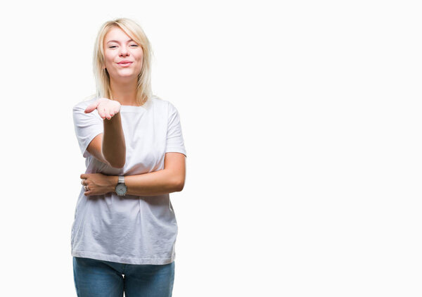 Young beautiful blonde woman wearing white t-shirt over isolated background looking at the camera blowing a kiss with hand on air being lovely and sexy. Love expression.