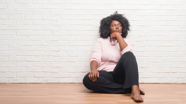Молодая Африканская Американка Сидящая Полу Наушниках Рукой Подбородке Думает Вопросе — стоковое фото