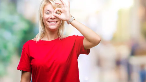 幸せそうな顔で指を通して見る目の手で のジェスチャーを行う分離の背景に赤い シャツを着て若い美しいブロンドの女性 — ストック写真