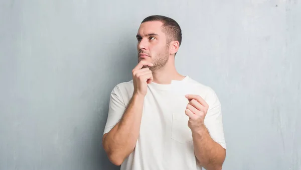 Joven Caucásico Hombre Sobre Gris Grunge Pared Mostrando Blanco Tarjeta — Foto de Stock