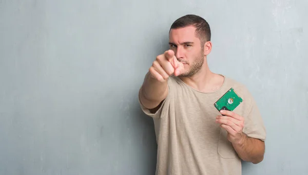 Young Caucasian Man Grey Grunge Wall Holding Hard Drive Pointing — Stock Photo, Image